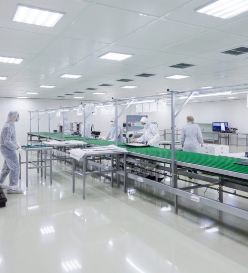 factory workers in white lab suits and face masks, producing tv sets on assebly line with some modern equipment